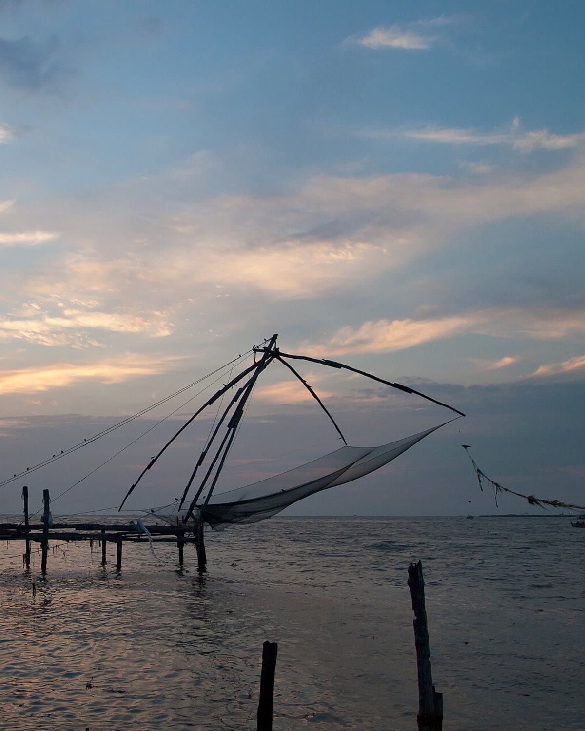 A Chinese fishing net on the Kochi waterfront at sunset.