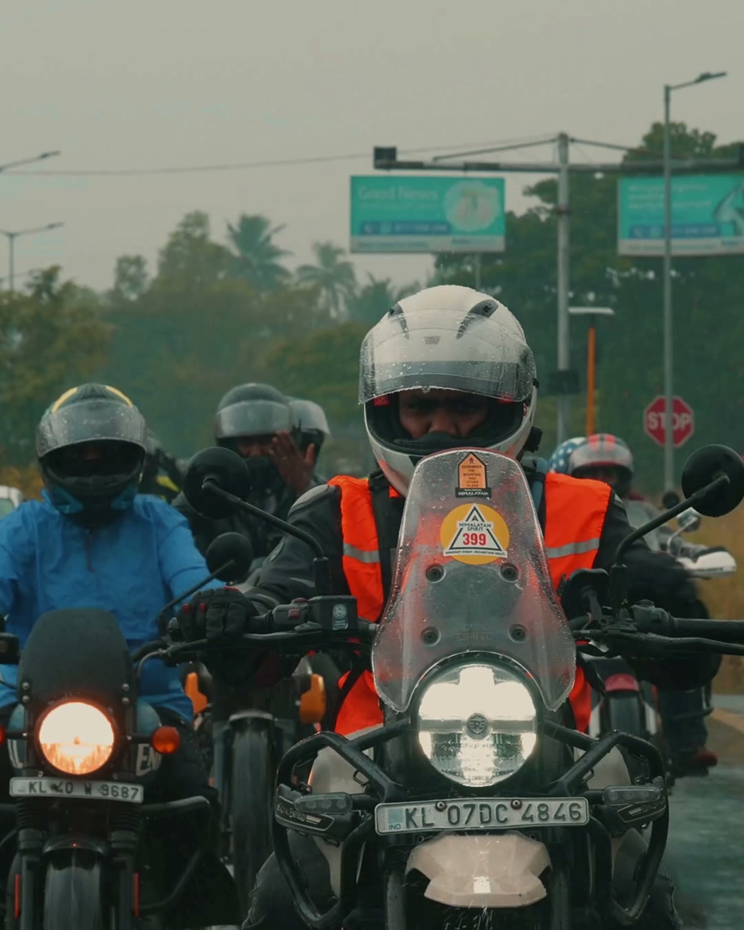 Royal Enfield riders in helmets and rain gear moving through a Kochi road at dawn.