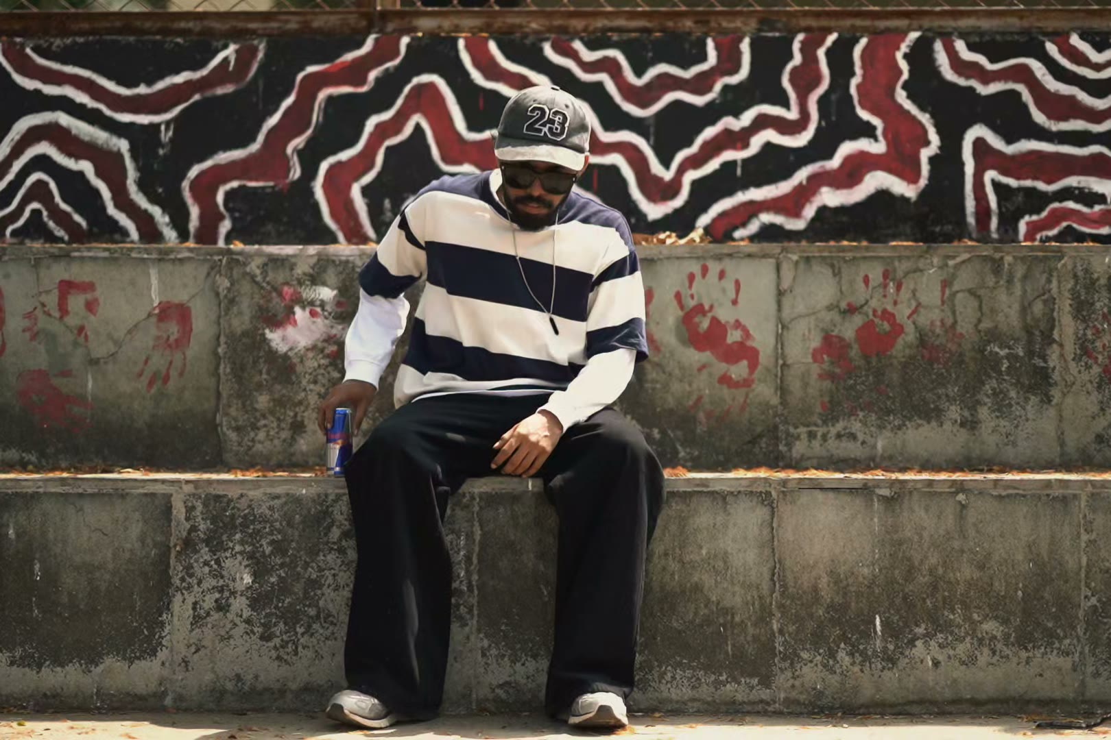 A model in a striped sweatshirt sitting in front of a painted wall.